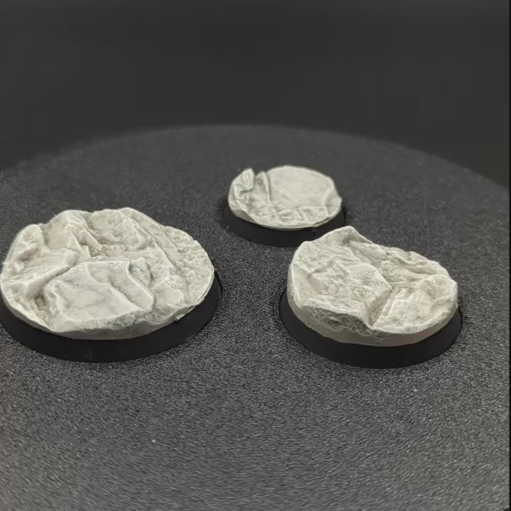 Three painted bases from the Txarli Rocky set rotating on a turntable. 25mm, 32mm and 40mm