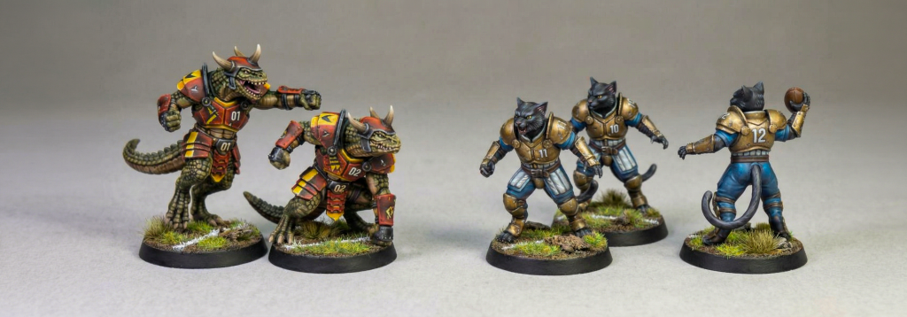 Two fantasy football teams facing off against one another. On the left 2 Samurai Lizardfolk in red and yellow. On the right 3 Renaissance Black Cats in brass armour with blue and white trousers.